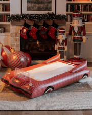Inflatable red car sleepover bed air mattress in a festive living room with Christmas stockings and decor.